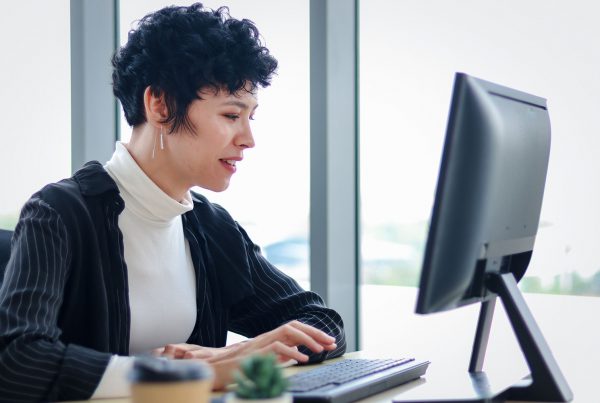 Smart and elegant smiling business woman lady with black short hair using desktop computer at the office desk